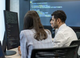Software developers checking programming code on computer screen.